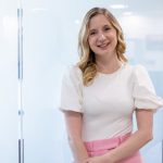 Rachel Harris, founder of striveX, dressed in a white t-shirt and pink trousers.