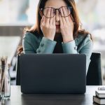 Student looking stressed while sat in front of her laptop at a desk